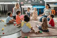Kindergruppe sitzt im Kreis mit Erzieherinnen