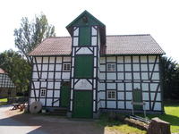 Gutswasserm�hle: historisches Fachwerkgeb�ude mit gr�n lackierten T�ren und Fensterl�den unter rotem Ziegeldach.