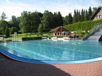 Schwimmbecken des Waldfreibads Preu�isch Oldendorf mit klarem Wasser, Liegewiese, Sonnenschirmen und B�umen im Hintergrund.
