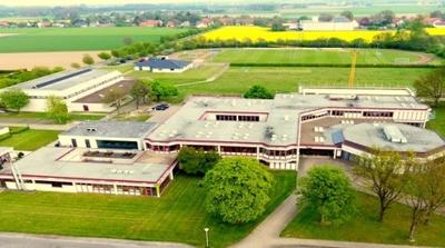 Luftaufnahme der Sekundarschule Preu�isch Oldendorf: ein flacher Schulkomplex mit mehreren Geb�udefl�geln, umgeben von Rasenfl�chen, Sportpl�tzen und Feldern.